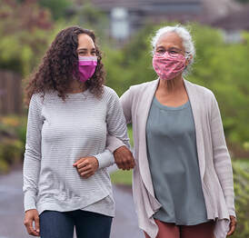 Woman walking arm in arm with mother, masked against the spread of COVID-19